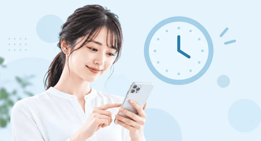 時計を背景にスマートフォンで申込時間を確認する女性